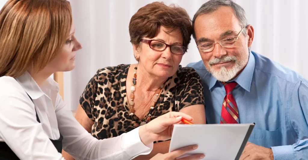 Couple de seniors écoutant les explications d'une conseillère en prévoyance.